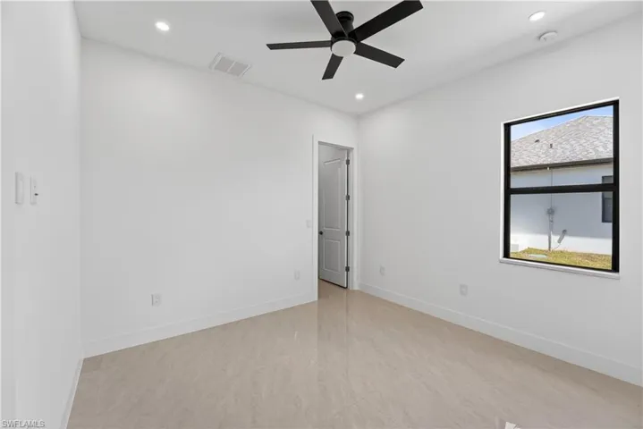 Bright interior space featuring large format tile flooring, a modern black ceiling fan, recessed lighting, and a window with a black frame