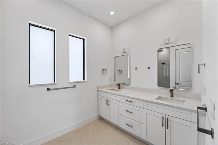 Dual vanity with white cabinetry, light-toned countertops, and bronze-finish fixtures