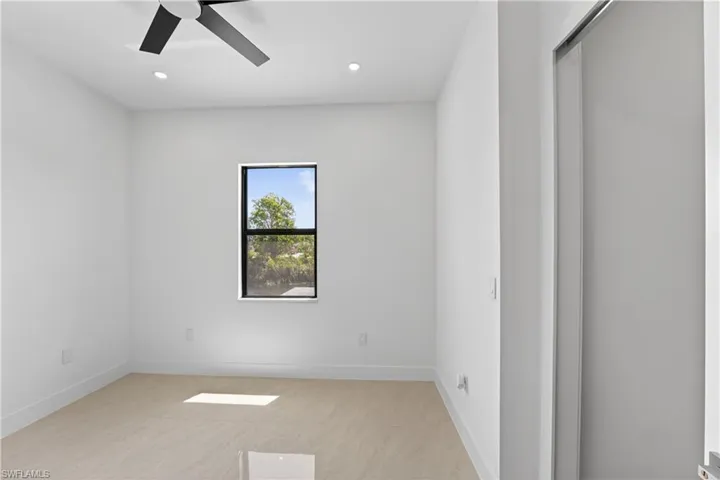 Bright interior space featuring a window with exterior tree scenery, a modern ceiling fan, recessed lighting, and tile flooring