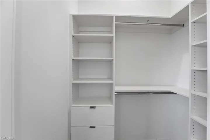 Custom closet system featuring white built-in shelving, two integrated drawers with modern pulls, and dual chrome hanging rods