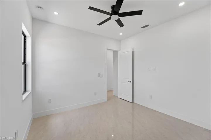 Contemporary interior space featuring light-toned large format tile flooring, a black ceiling fan, recessed lighting, and a white paneled door