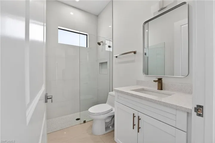 Modern bathroom featuring a glass-enclosed shower with tile surround, a built-in shower niche, and a transom window