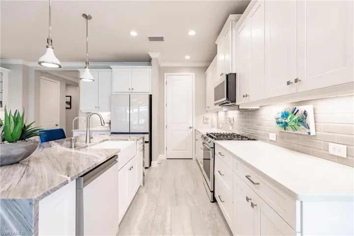 Bright white kitchen with granite island and solid surface counters along the walls. New glass backsplash.