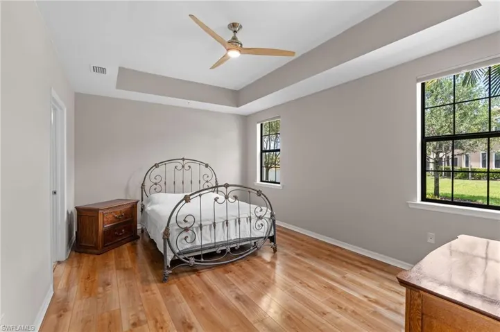Bedroom featuring multiple windows, light wood-type flooring, and a raised ceiling