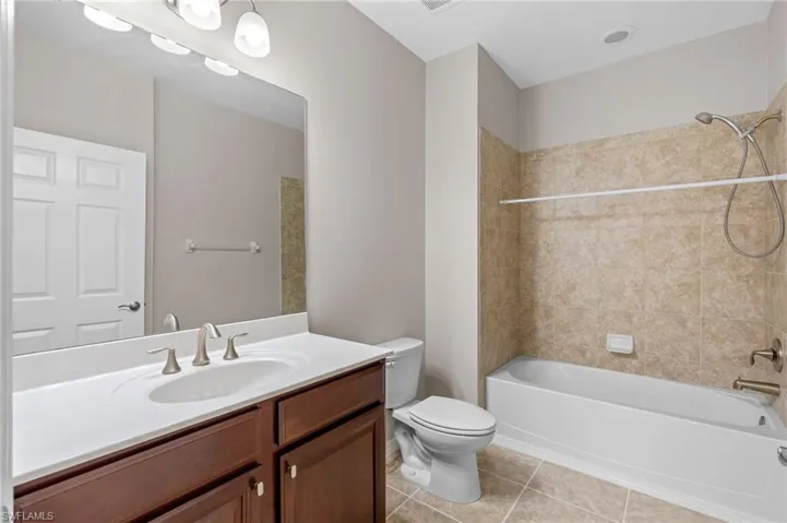 Full bathroom featuring toilet, washtub / shower combination, vanity, and tile patterned floors
