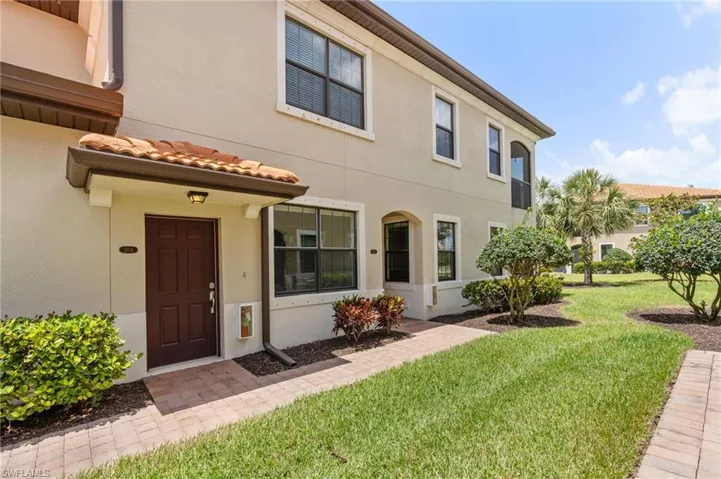 View of front of home featuring a tile roof, a front lawn, and stucco siding