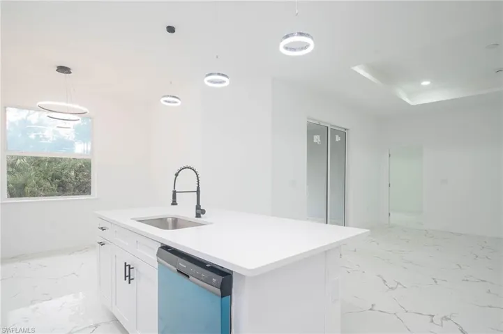 Kitchen featuring light marble finish flooring, dishwashing machine, white cabinetry, decorative light fixtures, and recessed lighting