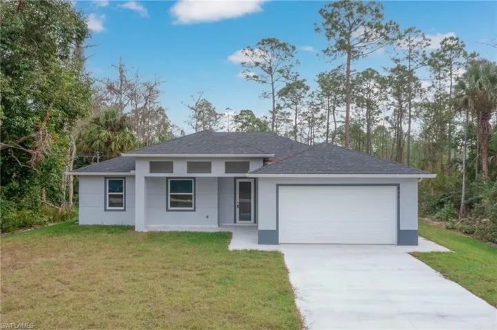 View of front facade with a front yard, a garage, driveway, and a shingled roof