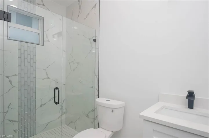Bathroom featuring a marble finish shower and vanity