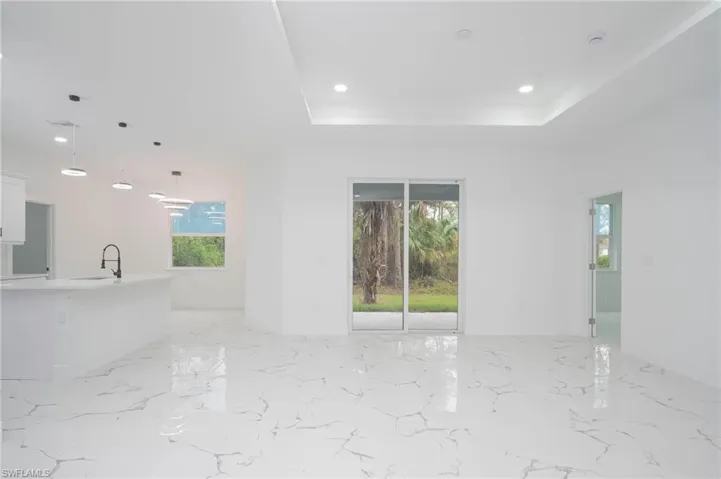 Unfurnished living room featuring a tray ceiling, recessed lighting, and light marble finish flooring