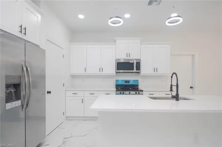 Kitchen with appliances with stainless steel finishes, light countertops, white cabinetry, recessed lighting, and light marble finish floors