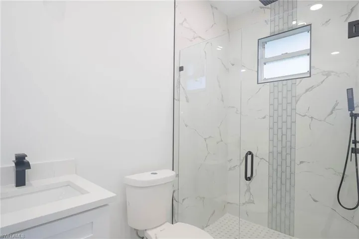 Bathroom featuring a marble finish shower and vanity