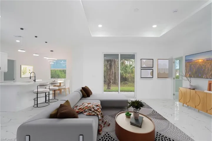 Living area featuring marble tiled flooring, a raised ceiling, and recessed lighting