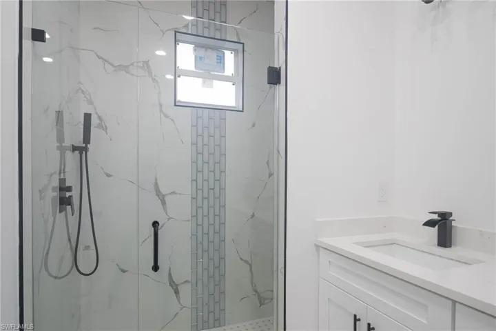 Full bathroom with a marble finish shower and vanity