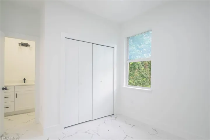Unfurnished bedroom with light marble finish flooring, a closet, and connected bathroom