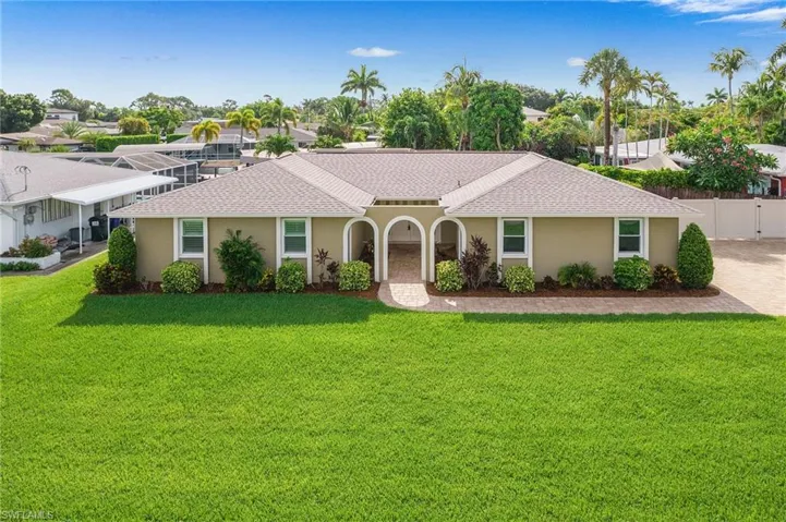 Single-story residence featuring a neutral-toned exterior, a gabled roofline, and a mature green lawn