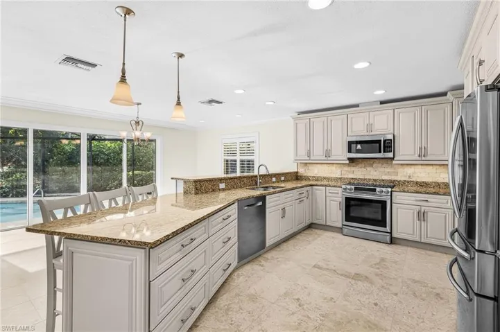 Spacious kitchen featuring light-toned cabinetry, stainless steel appliances, granite countertops, and tile flooring