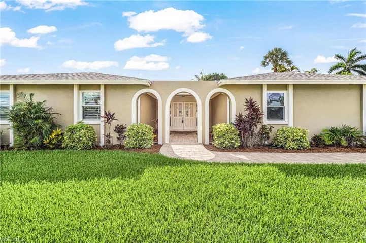 Stucco exterior featuring an arched entryway with decorative double doors