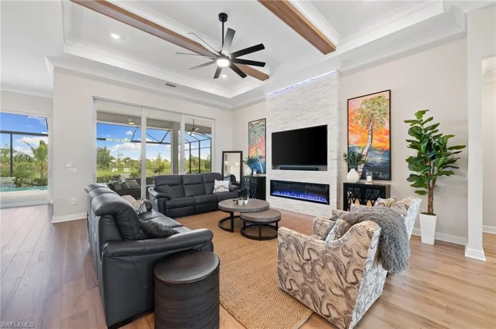 Living room with ceiling fan, a fireplace, light hardwood, and abundant natural light