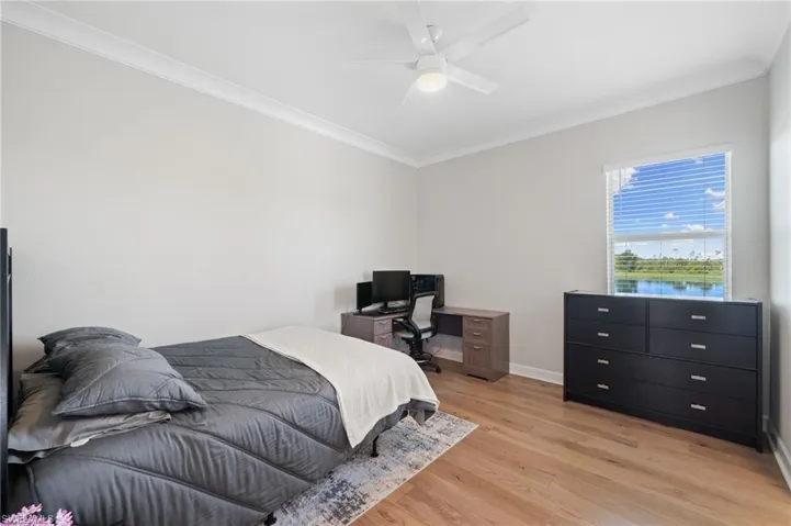 Bedroom featuring light hardwood floors, crown molding, and ceiling fan