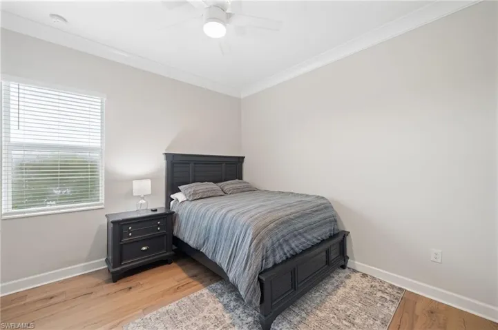 Bedroom with crown molding, light hardwood flooring, and ceiling fan