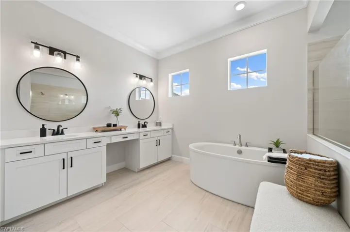 Bathroom featuring plank tile, crown molding, a separate tub, and double vanity
