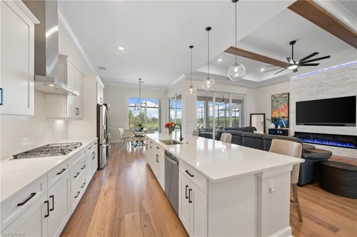 Kitchen featuring sink, light hardwood / wood-style flooring, ceiling fan with notable chandelier, and a large island