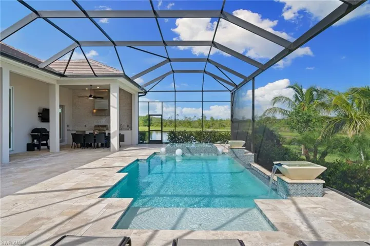 View of pool featuring pool water features, screen enclosure, a patio area, outdoor kitchen and ceiling fan