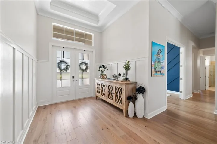 Entryway featuring double doors, a shiplap tray ceiling, light hardwood, a towering ceiling, and crown molding