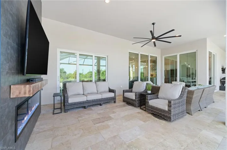 Outdoor TV area featuring a fireplace and extra large ceiling fan