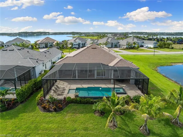 Rear view of property featuring a water view, an oversized screened lanai and yard