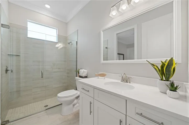 Bathroom featuring an enclosed shower, plank tile, vanity, crown molding, and toilet