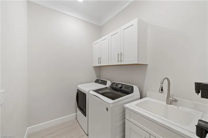 Laundry room featuring crown molding, sink, cabinets, independent washer and dryer, and plank tile
