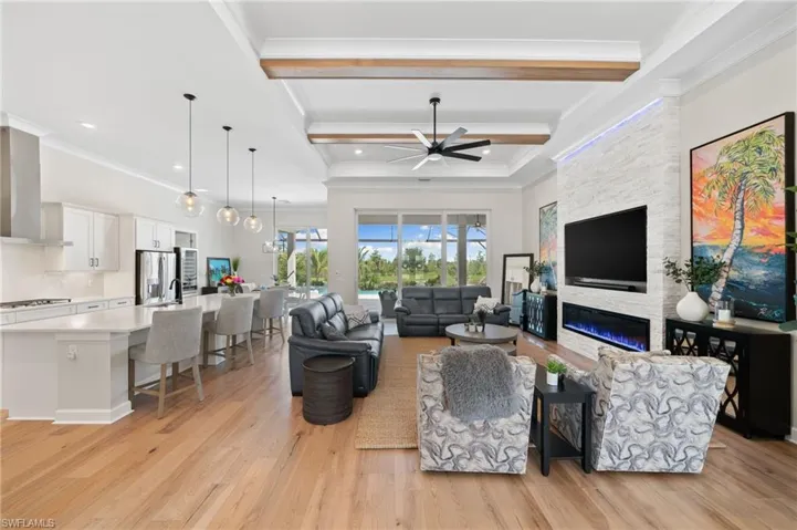 Living room featuring light hardwood flooring, a fireplace, Feature wall, beam ceiling, and ceiling fan