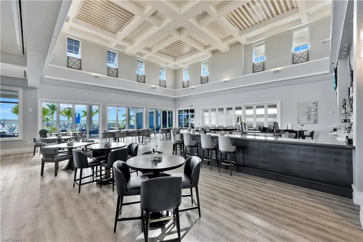 Dining area featuring light hardwood floors, coffered ceiling, beamed ceiling, and a high ceiling