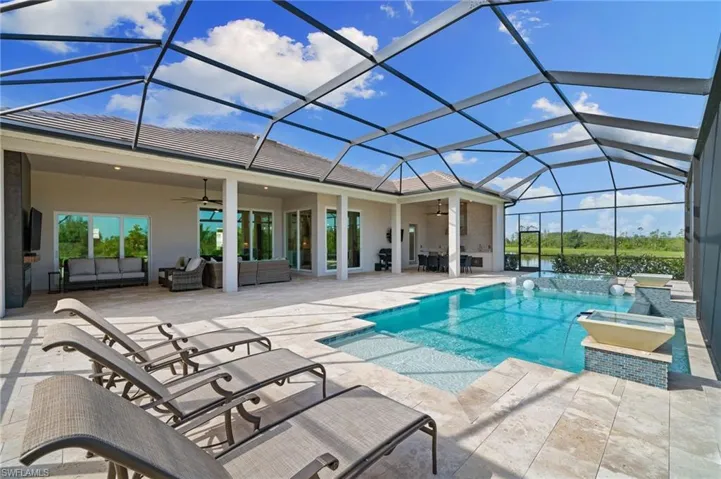 View of pool with lanai, ceiling fan, an outdoor hangout area, and a hot tub and water views