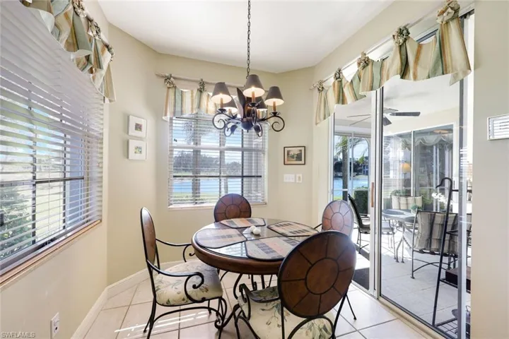 Tiled dining room with ceiling fan, hanging lights, and plenty of natural light