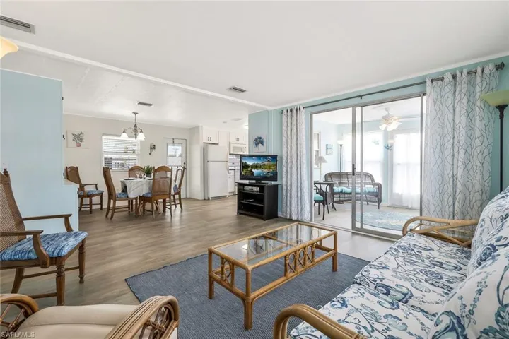 Living area with wood finished floors, visible vents, and an inviting chandelier