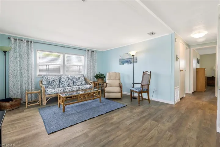 Living area featuring baseboards, wood finished floors, visible vents, and crown molding