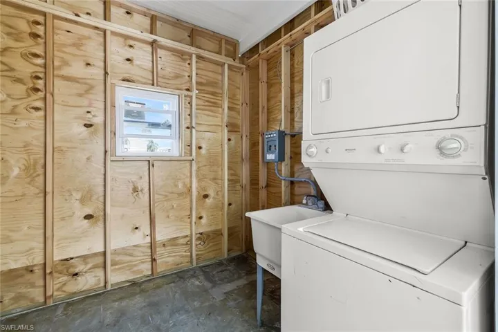 Laundry area with stacked washer and dryer, laundry area, and a sink