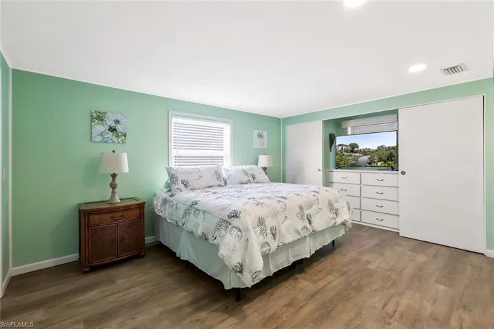 Bedroom with dark wood finished floors, baseboards, and multiple windows