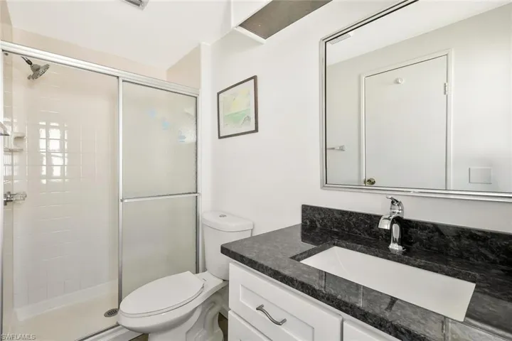 Bathroom featuring a shower stall, toilet, and vanity