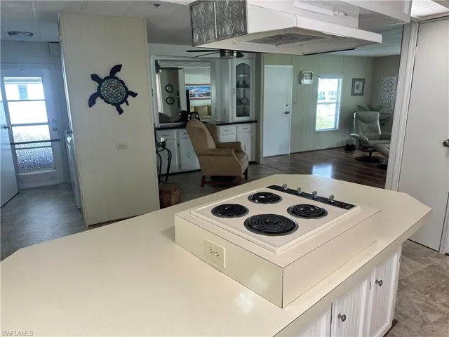 Kitchen featuring stove, white cabinetry, exhaust hood, and hardwood / wood-style flooring