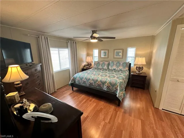 Bedroom with light hardwood / wood-style flooring, multiple windows, and ceiling fan