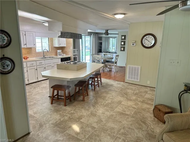 Kitchen with white cabinets, sink, light hardwood / wood-style floors, a kitchen breakfast bar, and ceiling fan
