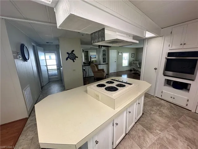 Kitchen featuring white cabinets, a healthy amount of sunlight, and stainless steel oven