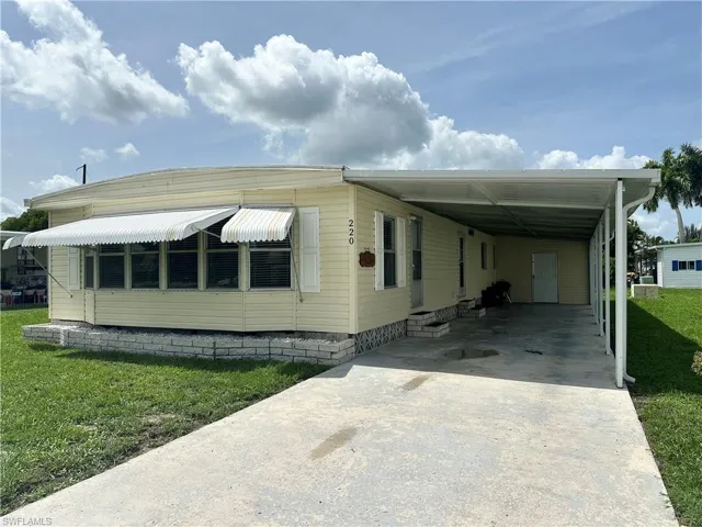 Manufactured / mobile home featuring a carport and a front yard