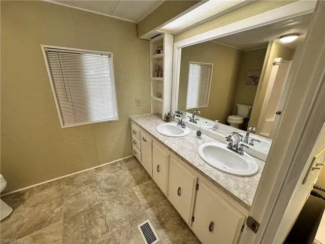 Bathroom featuring tile patterned flooring, toilet, and dual bowl vanity