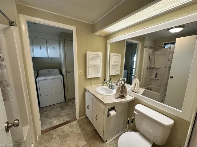 Full bathroom with shower / bath combination with curtain, tile patterned flooring, washer / clothes dryer, toilet, and vanity