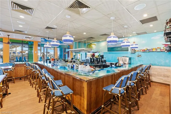 Bar area featuring a drop ceiling, decorative light fixtures, and wood finish cabinetry